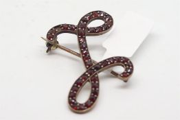 Garnet set scroll brooch, channel and bead set, in low carat, yellow metal