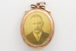 Oval yellow metal picture frame locket, with a bow detail to the top, and a pendant loop, stamped