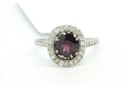 Garnet and diamond cluster ring, central oval cut garnet, surrounded by round cut diamonds and