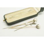 Four natural pearl stick pins, including a pearl stick pin designed as a diamond set dragon claw