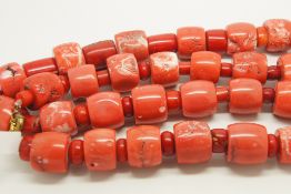 Long row of coral beads, large coral barrel shaped beads, each separated by a red coral bead,