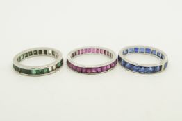 Three full eternity rings, one set with rubies, one sapphires, one emeralds, mounted in platinum,