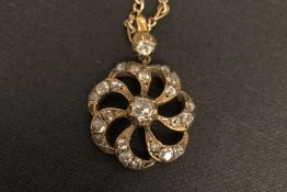 Diamond cluster pendant, pinwheel design set with old cut diamonds on a yellow metal chain.