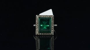 A green paste ring in a white metal mount with a halo of white stones, ring size J 1/2