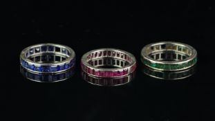 Three full eternity rings, one set with rubies, one sapphires, one emeralds, mounted in platinum,