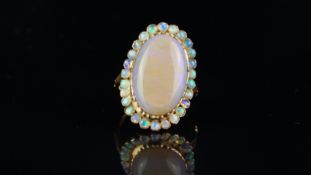 Opal ring, central light opal measuring 19 x 12.68 x 4.83mm, surrounded by small round cabochon