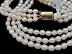 A three row pearl necklace, graduated length rows of cultured pearls, on a yellow metal plated