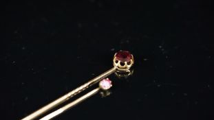 Two stick pins, one set with an old cut almandine garnet, the other set with a cushion cut ruby,
