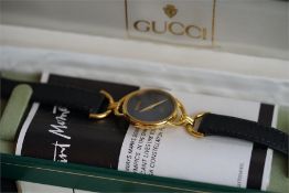 LADIES GUCCI DRESS WATCH circular black dial, gold plated ase, black leather strap, model number