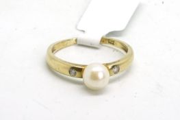Pearl and diamond ring, central 5.6mm pearl, with a rubover set round brilliant cut diamond set each