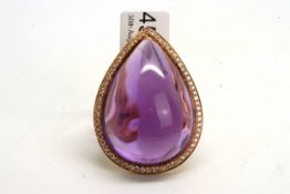 An amethyst and diamond domed ring, set with a cabochon cut pear shaped amethyst weighing an