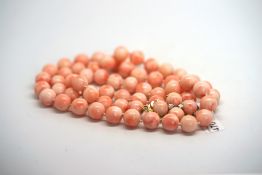 Coral bead necklace, 9.5mm coral beads, strung knotted on a yellow metal clasp, set with half