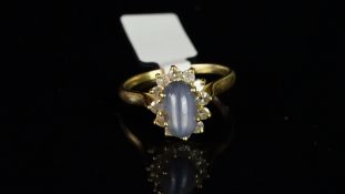 Star sapphire and diamond ring, oval cabochon cut star sapphire, four claw set, with a surround of
