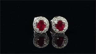 Ruby and diamond stud earrings, set with a central oval cut ruby, surrounded by round brilliant