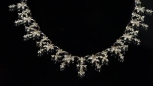 Floral diamond necklace, designed as diamond set floral drops in a repeating pattern, set to the