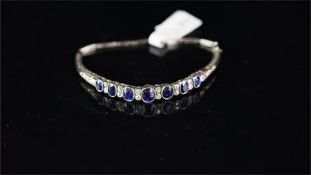 Sapphire and diamond bangle, seven graduated oval cut sapphires, measuring from 6 x 4.8 to 4.5 x 3.