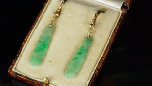 A pair of jade earrings, each with a floral carved drops, suspended from a trace link chain and