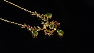 An Art Nouveau peridot, ruby and seed pearl necklace, floral design with three pear cut peridot
