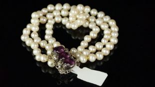 Three strand pearl bracelet, 5.5mm pearls on a white metal clasp stamped 935, set with purple and