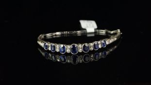 Sapphire and diamond bangle, seven graduated oval cut sapphires, measuring from 6 x 4.8 to 4.5 x 3.
