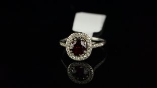 Garnet and diamond cluster ring, central oval cut garnet, surrounded by round cut diamonds and