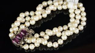 Three strand pearl bracelet, 5.5mm pearls on a white metal clasp stamped 935, set with purple and