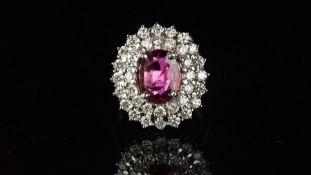 Ruby and diamond oval cluster ring mounted in white metal stamped 750, central oval shaped ruby with