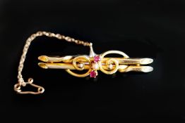 Victorian bar brooch, set with a central pearl and two round cut rubies, mounted on a yellow metal