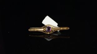 An amethyst bar brooch, central round amethyst to the central of a decorative bar brooch, mounted in