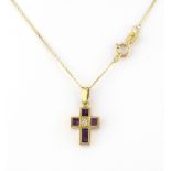 A ruby and diamond set cross pendant. The 18kt yellow gold pendant designed as a Latin cross,