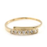 A diamond set ring. The ring designed as a tapered crossover band, set to the front with a row of