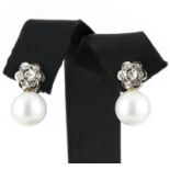 A pair of diamond and pearl set earrings. The cultured South Sea pearls suspended below floral