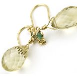 A pair of citrine and emerald earrings. The pale yellow faceted citrine drops suspened below