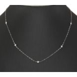 A diamond set necklace. The trace link chain set at intervals with bezel set brilliant cut diamonds,