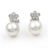 A pair of South Sea pearl and diamond earrings. The cultured pearls suspended below floral cluster