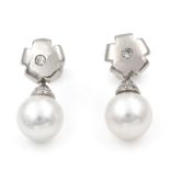 A pair of diamond and cultured pearl earrings. The saltwater cultured pearls with diamond set cap