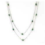 An emerald set necklace. The necklace designed as two 18kt white gold chains set at regular