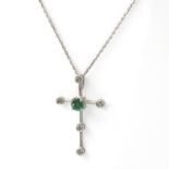 An emerald and diamond set cross pendant. The Latin cross centrally set with a claw set, round cut