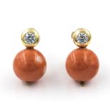 A pair of coral and cubic zirconia earrings. The spherical pacific coral beads each suspended