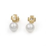 A pair of diamond and South Sea pearl earrings. Each cultured pearl suspended from a polished