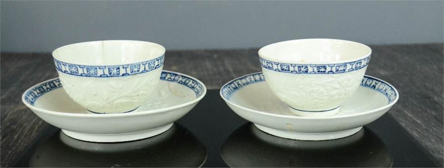 A pair of early English tea bowls and saucers, embossed with flowers, blue and white borders.