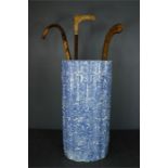 A blue and white umbrella stand together with three walking sticks.