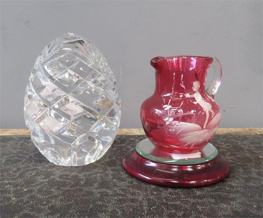 A gut glass egg form paperweight together with a Victorian cranberry glass jug.