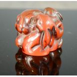 A Japanese red jade bead, signed to the base, in the form of a rabbit and her kits.