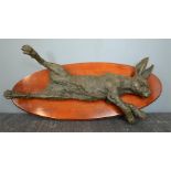 A bronze hare, with oval wooden plaque, 53cm long.