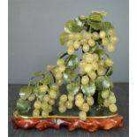 A large jade group composed of bunches of grapes, on a naturalistic wooden base, 33cm high by 33cm