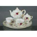 An antique porcelain miniature tea service, painted with flowers and having gilt decoration.
