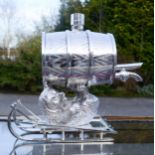 A silver plated barrel form whisky decanter in the form of a bear on a sledge.
