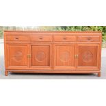 A Chinese hardwood sideboard, with carved panels to the cupboard doors.