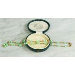 A jade bead necklace with yellow metal and seed pearl clasp.